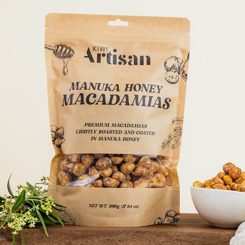 Bag of Kiwi Artisan Manuka Honey Macadamias on a wooden surface with a bowl of macadamias.