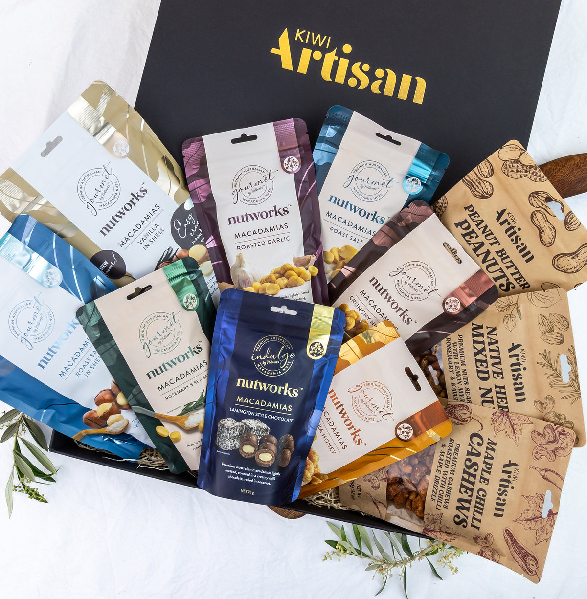 Kiwi Artisam Gourmet Nut Gift Box -  Assorted nut packages from various brands in front of a Kiwi Artisan box.