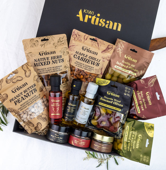 Assorted gourmet food items in a 'Kiwi Artisan' box on a white background
