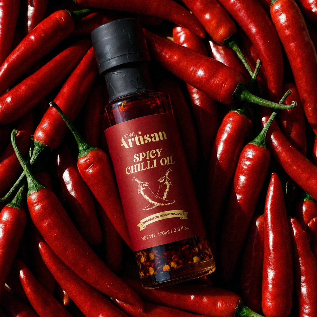 Bottle of Kiwi Artisan Spicy Chilli Oil surrounded by red chili peppers