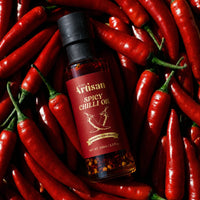 Bottle of Kiwi Artisan Spicy Chilli Oil surrounded by red chili peppers