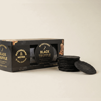 Black truffle crackers with packaging on a beige background