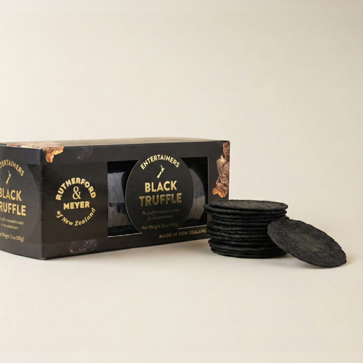 Black truffle crackers with packaging on a beige background