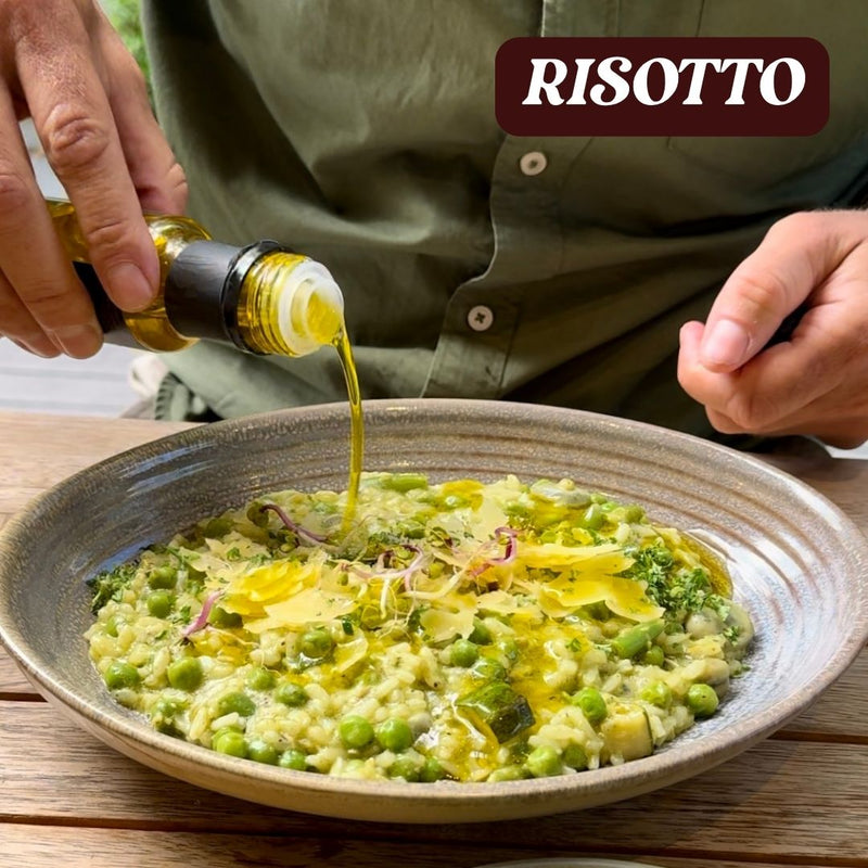 Person pouring oil over a dish of risotto with peas and broccoli, with 'RISOTTO' branding.