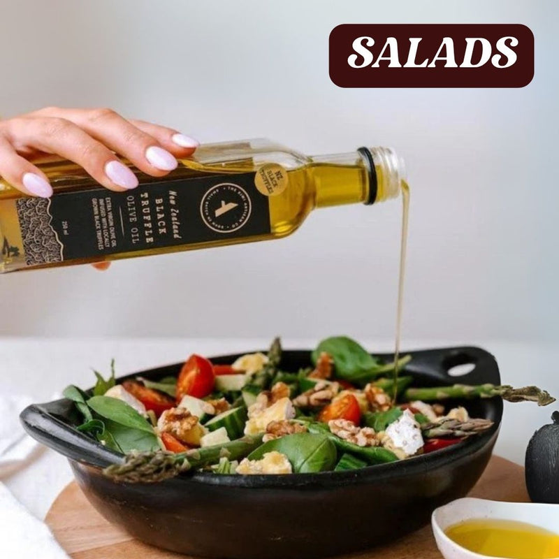Person pouring black truffle olive oil over a salad with 'SALADS' text at the top.